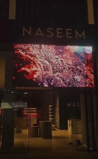 P4 outdoor LED screen displaying 'Naseem' at modern building