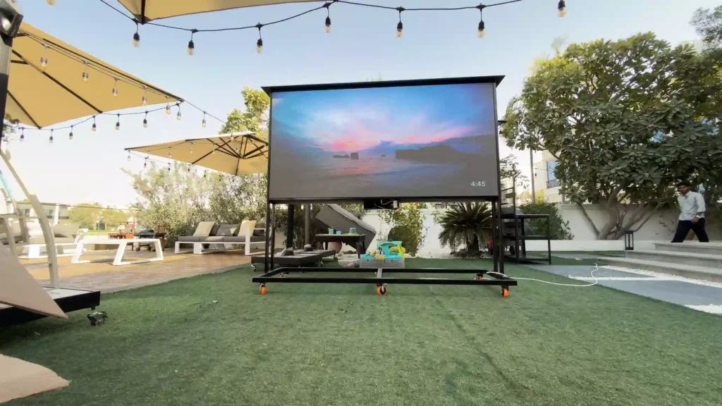 Outdoor LED screen on lawn displaying beach scene visual